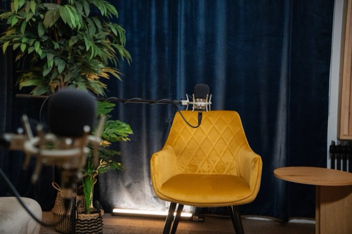 A mustard armchair and a boom microphone in front of the blue velvet curtain in Studio 1.